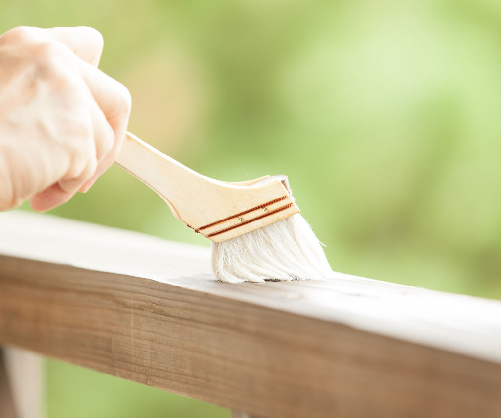 Aplikacja pędzlem Everwood Bio Varnish na elemencie drewnianego ogrodzenia